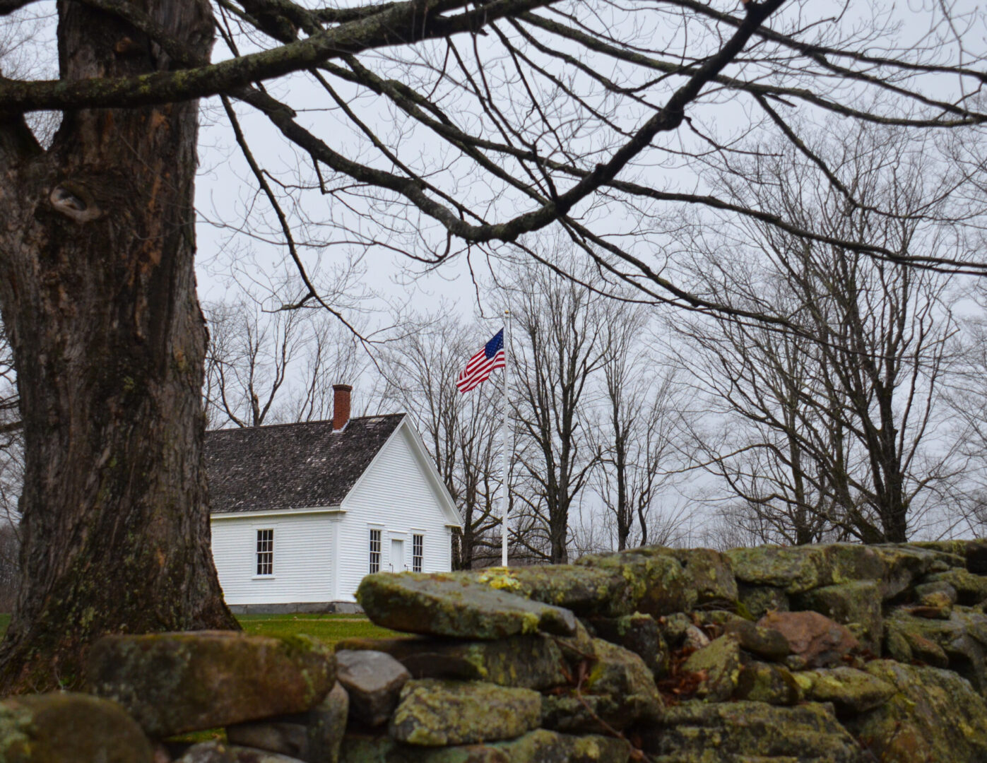 A white house with trees and a flag in the background