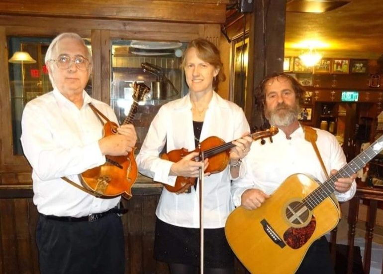 Three people are playing their instruments in a restaurant.