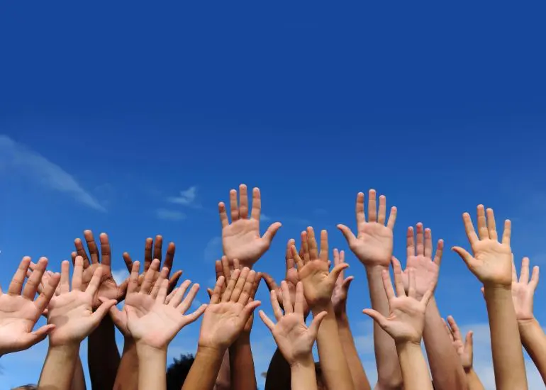 A group of people raising their hands in the air.