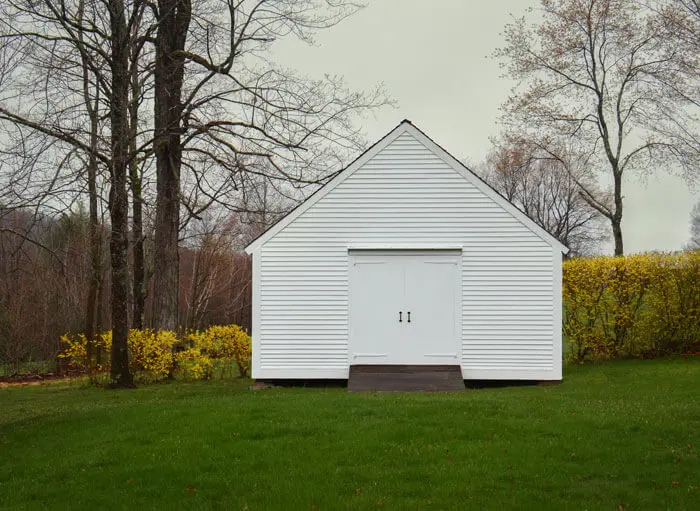 A white shed sitting in the middle of a field.